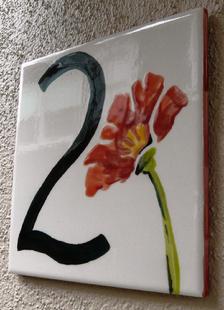 Photograph of one of the painted poppy address tiles that are next to each apartment door.