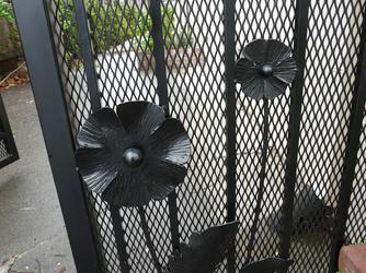 Close up photograph of black metal poppies that decorate the custom made artist designed poppy gate at the entrance to the property.